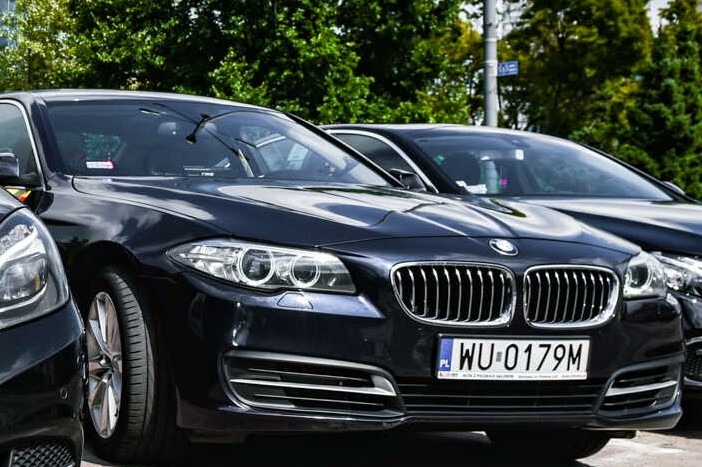 Ciemnogranatowe BMW serii 5 z polską tablicą rejestracyjną WU 0179M zaparkowane na ulicy, widoczne również fragmenty innych pojazdów.