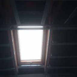 Montaż okna dachowego w konstrukcji poddasza z widoczną metalową konstrukcją nośną i częściowo zamontowaną izolacją.