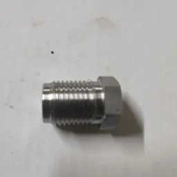 Metalowa śruba z gwintem, leżąca na szarej powierzchni. Widoczne ślady obróbki i niewielkie niedoskonałości powierzchni.