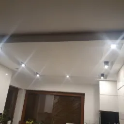 Nowoczesna kuchnia z białymi, lakierowanymi szafkami i oświetleniem punktowym w suficie podwieszanym, widok z dołu.