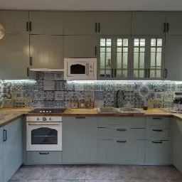 Kompletna kuchnia w odcieniach szarości i błękitu z drewnianymi blatami, wzorzystymi płytkami nad blatem, oświetleniem LED podszafkowym i przeszklonymi szafkami wiszącymi.