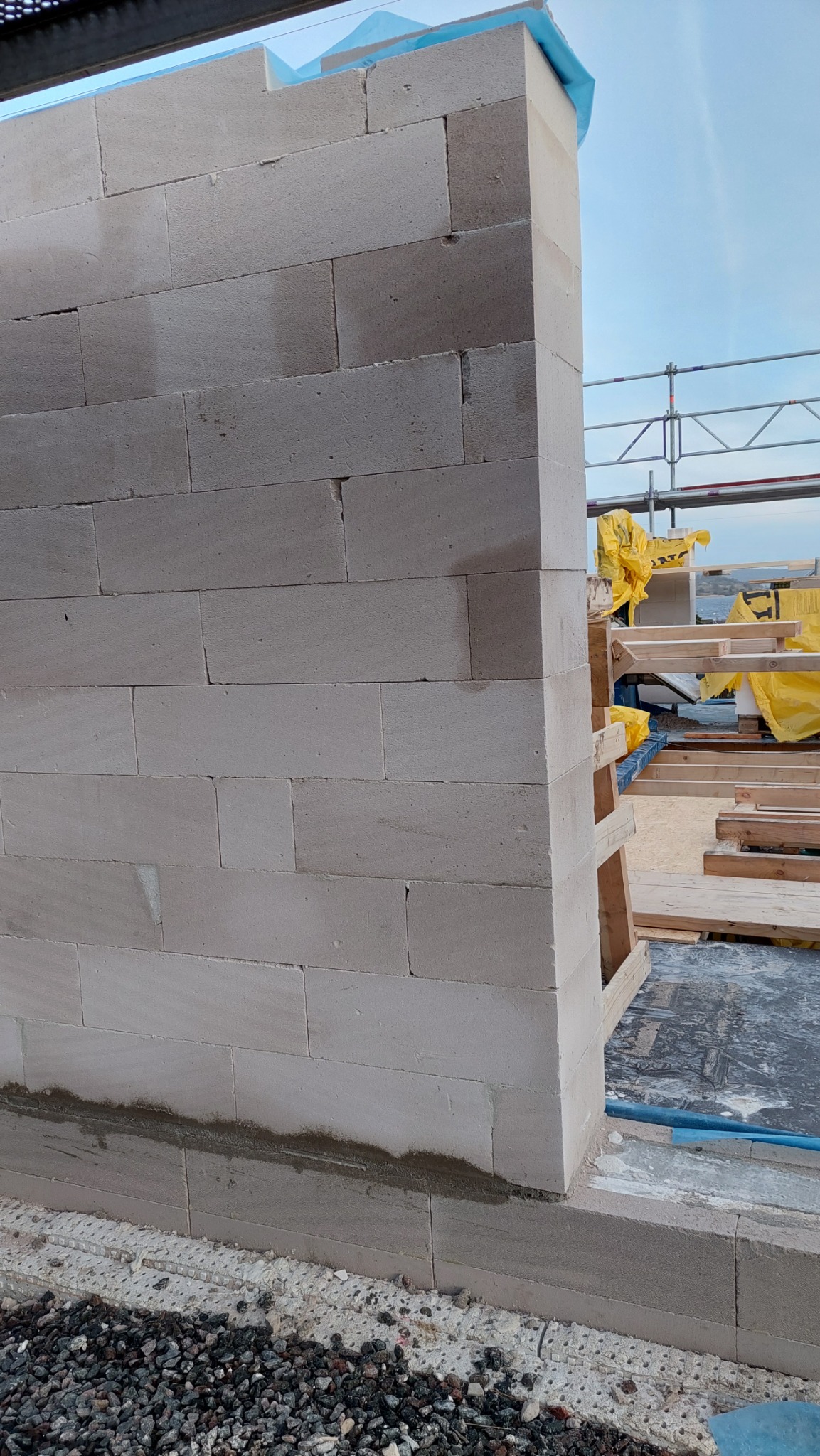 Wznoszenie ściany z bloczków z betonu komórkowego Ytong Silka, widoczne spoiny i fragment rusztowania w tle.