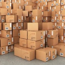 Stos kartonowych pudeł ułożonych w magazynie, niektóre z nadrukowanymi gwiazdkami i symbolami recyklingu, z widocznymi kodami kreskowymi i etykietami.