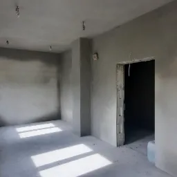 Surowe wnętrze po nałożeniu szarej warstwy tynku, widoczne okna z trzema szybami, sufit z wystającymi kablami oświetleniowymi oraz otwór drzwiowy z surowym wykończeniem.