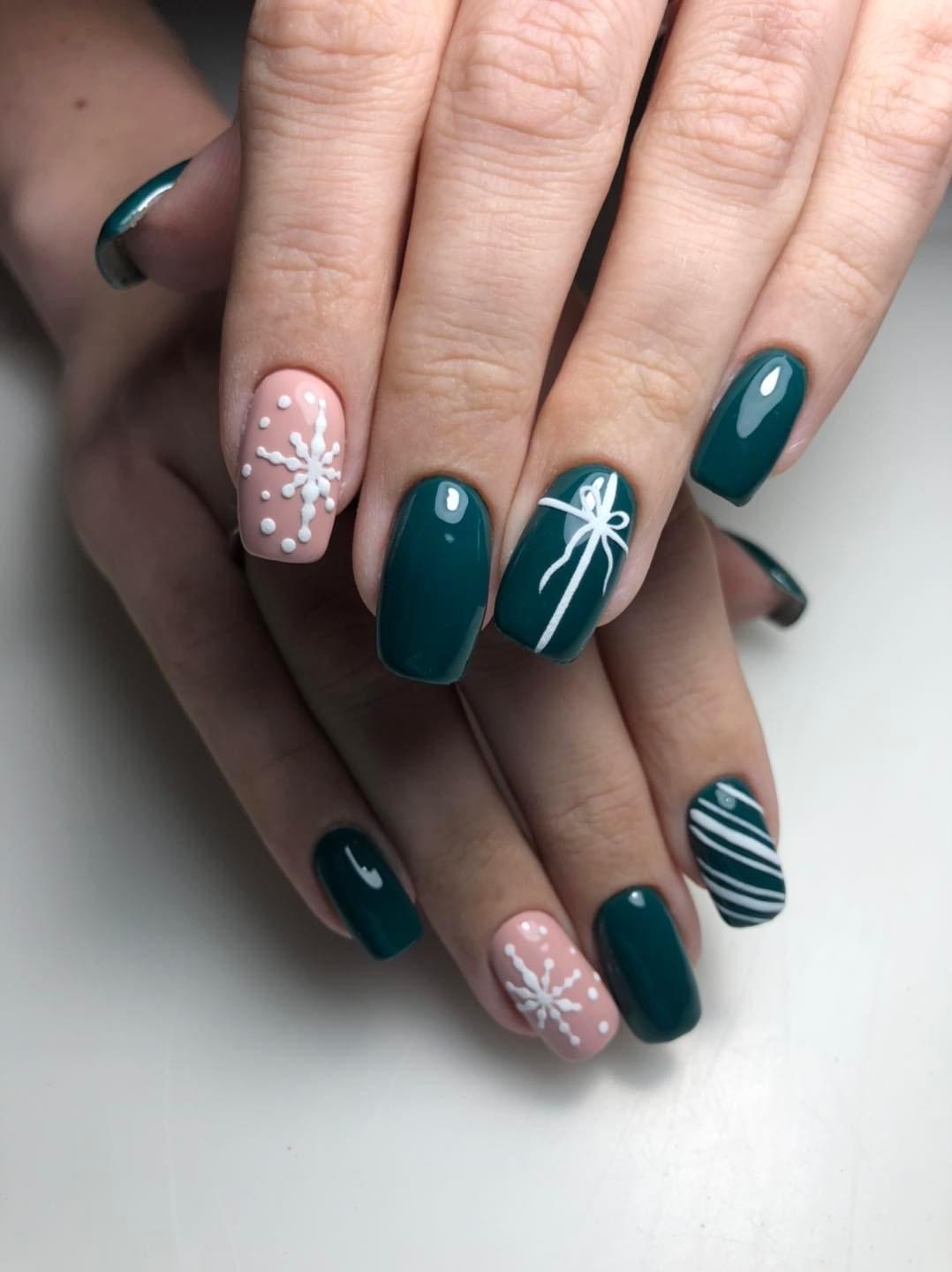 Zimowa stylizacja paznokci: ciemnozielone i pudrowo-różowe hybrydy z białymi wzorami śnieżynek, prezentu i pasków.