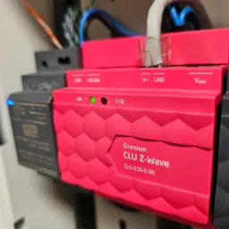 Centrala sterująca Grenton CLU Z-Wave z podłączonymi przewodami w szafie sterowniczej, widoczne diody sygnalizujące status urządzenia.