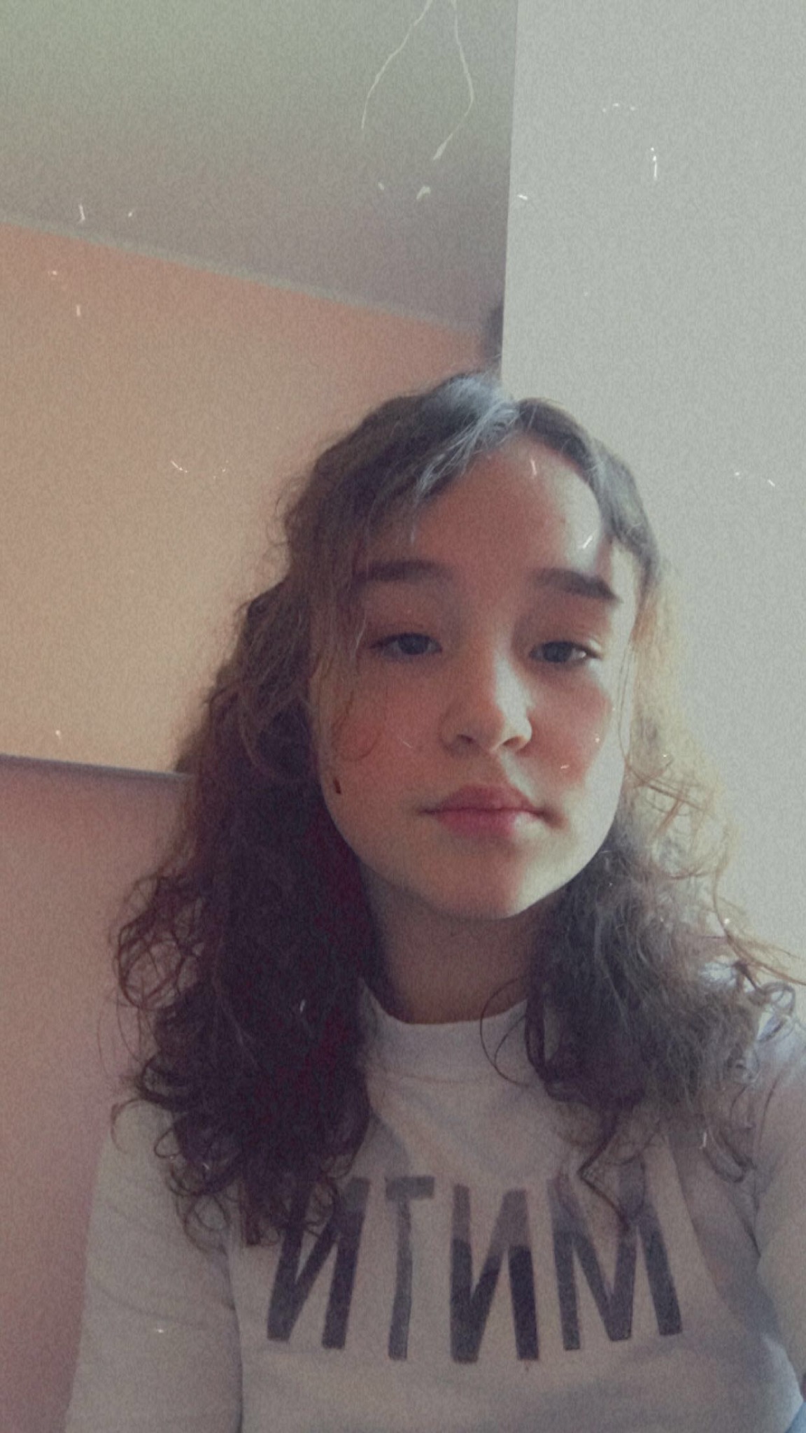 Portret młodej kobiety z kręconymi włosami i napisem na koszulce, z efektem starego filmu.