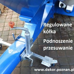Dekor PUHB - Niebieska konstrukcja z regulowanymi kółkami i podnośnikiem na kostce brukowej, widok z dołu.