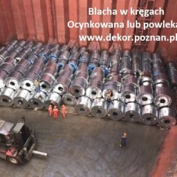 Dekor PUHB - Wnętrze ładowni statku wypełnionej kręgami blachy ocynkowanej, z widocznym wózkiem widłowym i kilkoma pracownikami w kombinezonach.