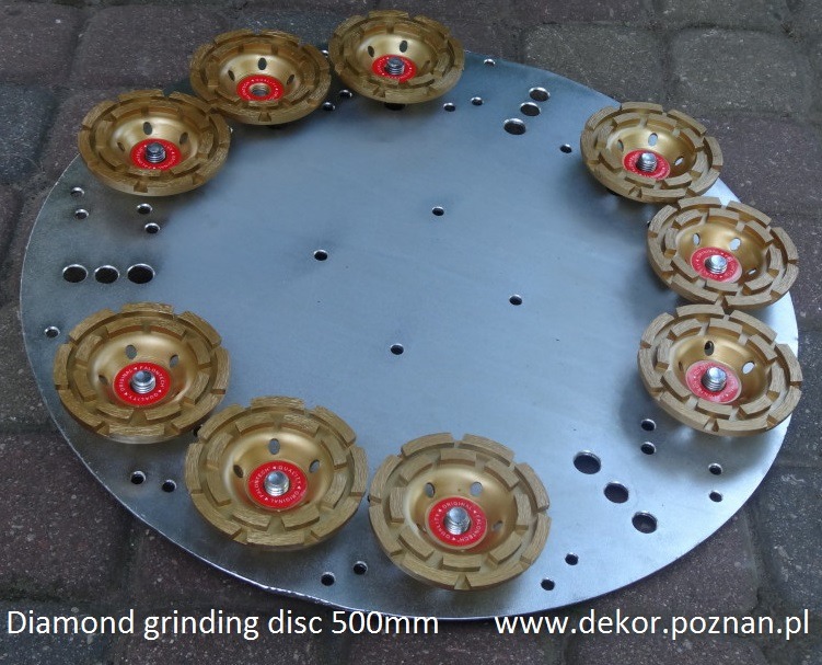 Okrągła, metalowa tarcza z zamocowanymi dziesięcioma złotymi ściernicami diamentowymi z czerwonymi etykietami na środku, ułożonymi w okrąg na szarym tle z kostki brukowej.