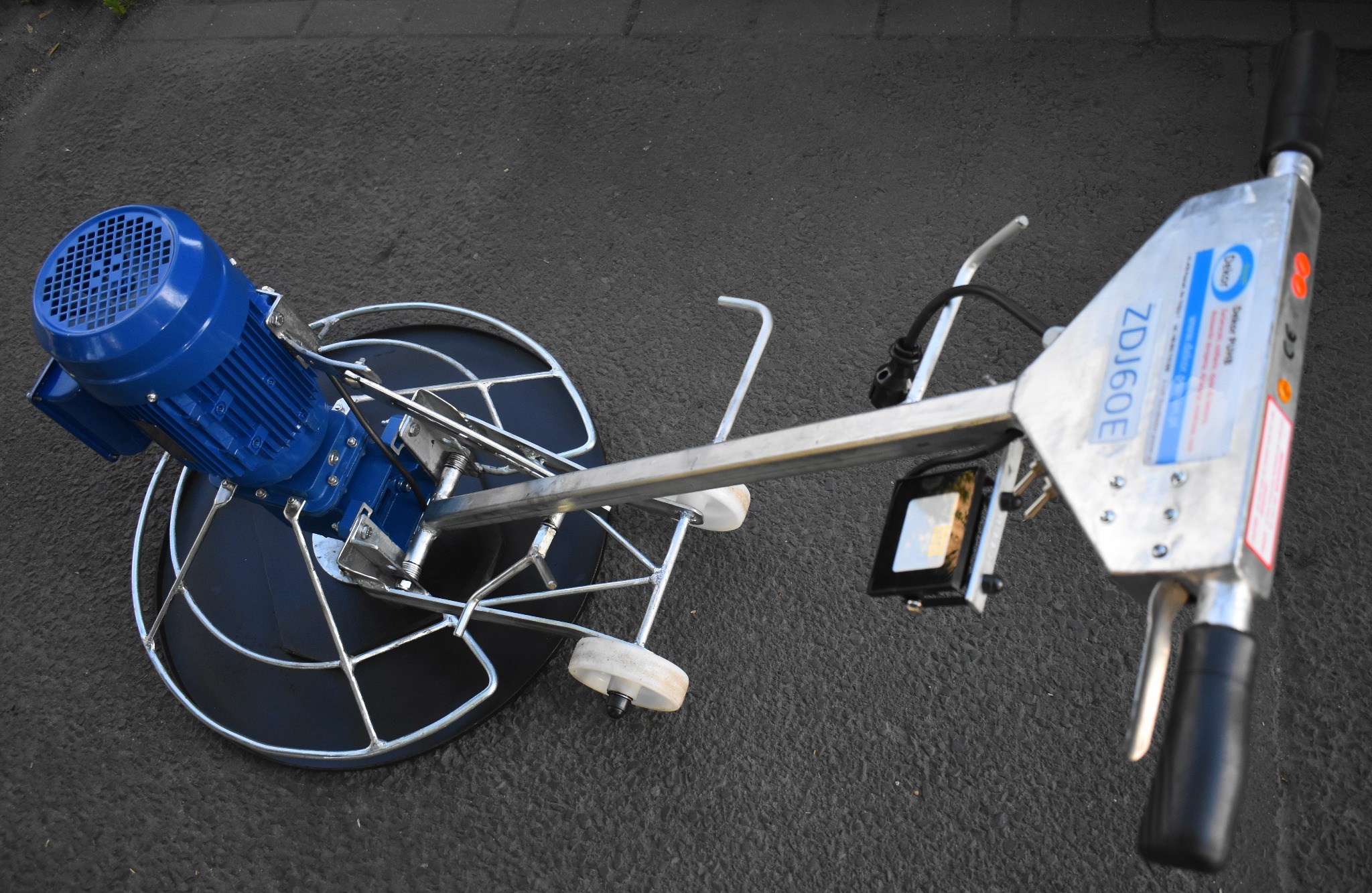 Zagęszczarka do betonu ZDJ60E z niebieskim silnikiem elektrycznym, widok z góry na szarym asfalcie.