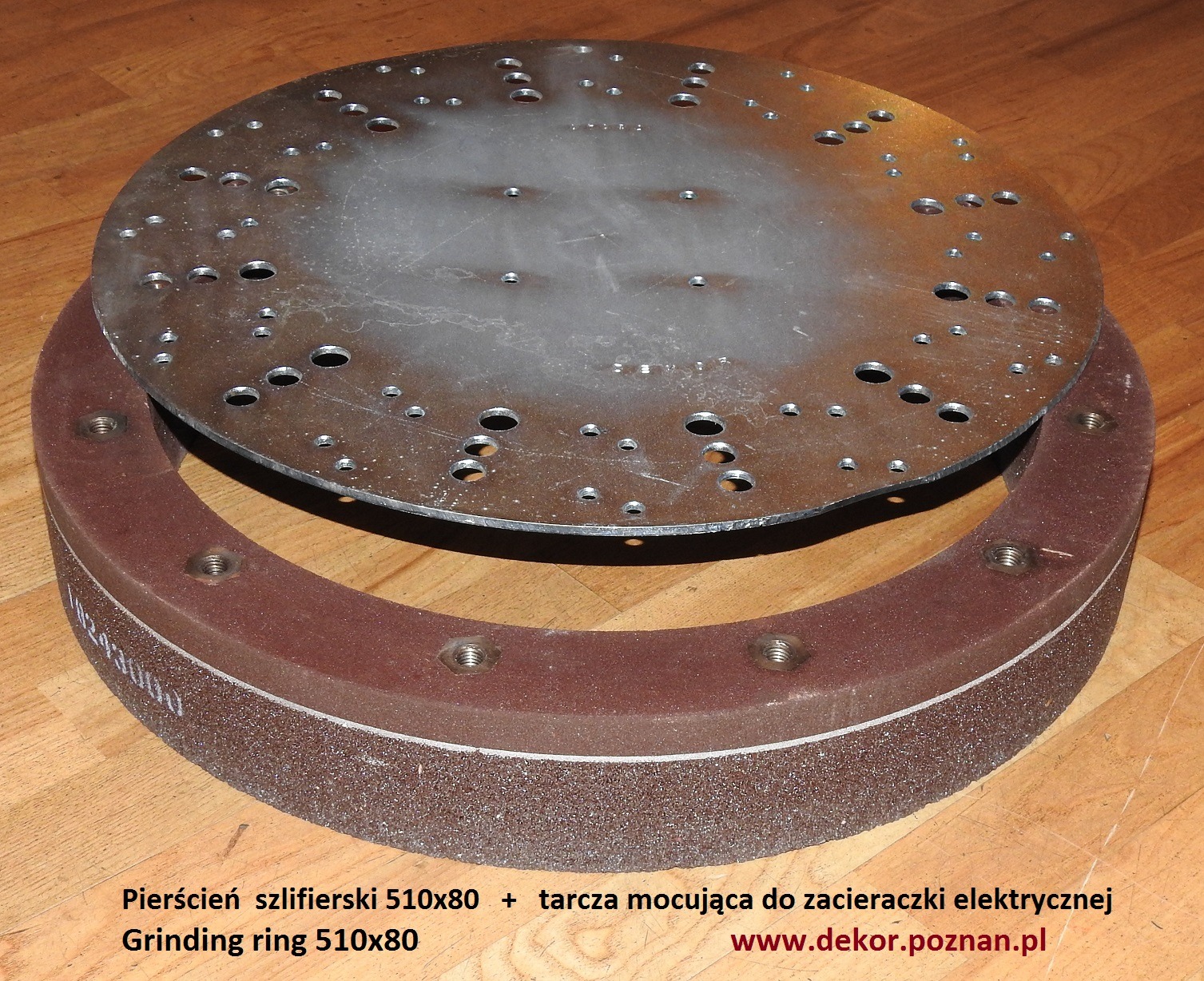 Pierścień szlifierski 510x80 z tarczą mocującą do zacieraczki elektrycznej, widoczne otwory montażowe i ziarnista struktura pierścienia, ułożone na drewnianej powierzchni.