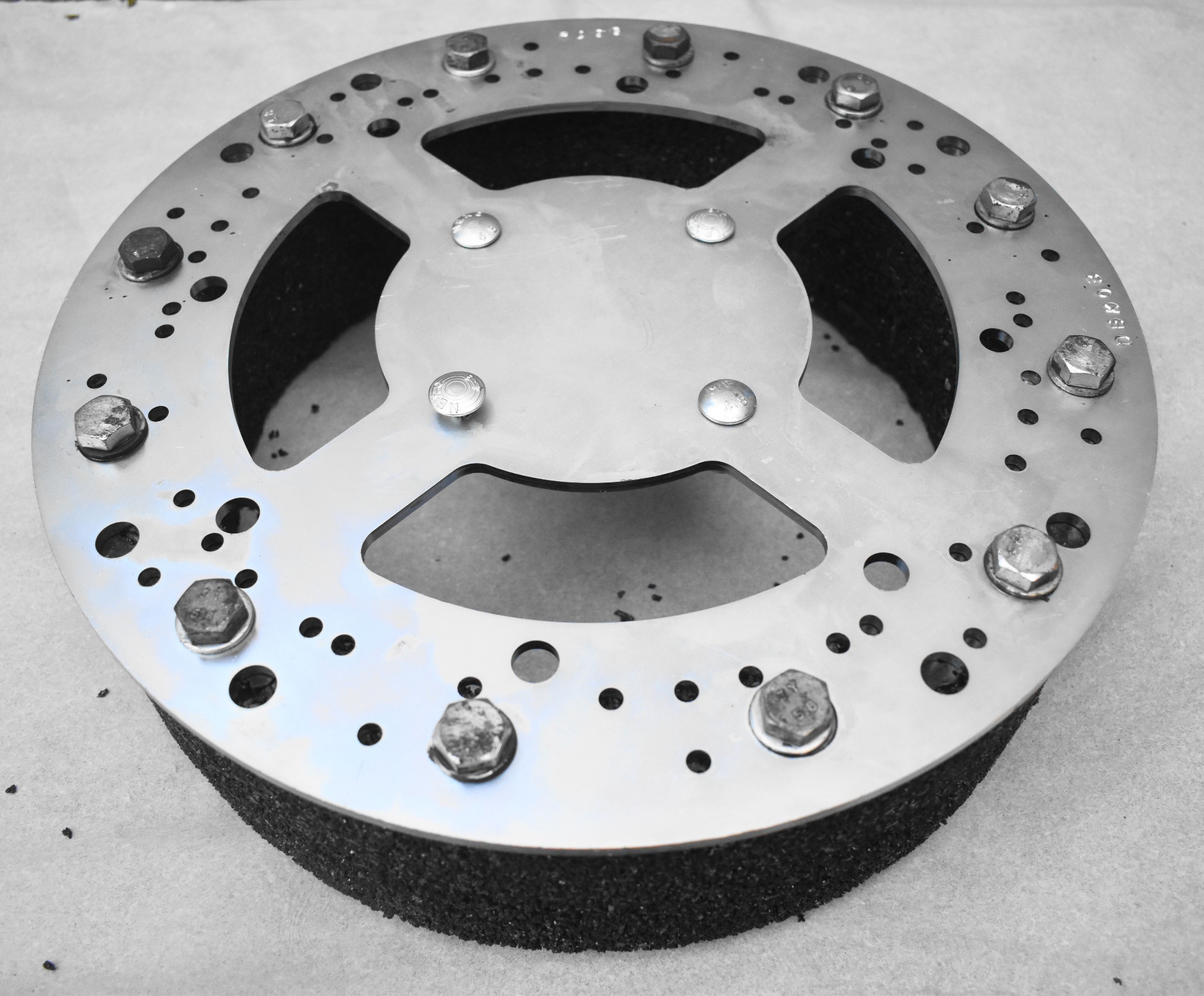 Tarcza szlifierska do betonu z metalowym korpusem mocowana śrubami, widoczne otwory i oznaczenia producenta.