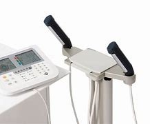 Profesjonalny analizator składu ciała z widocznym panelem sterowania i uchwytami do pomiaru, ustawiony na białym tle.