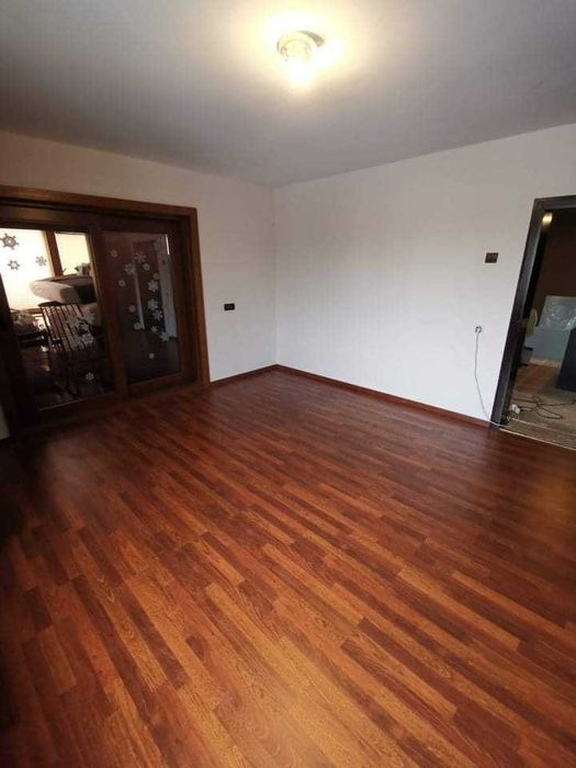 Pusty pokój po remoncie z nową, błyszczącą, brązową podłogą z paneli, świeżo pomalowanymi białymi ścianami i drewnianymi drzwiami przesuwnymi z dekoracjami w kształcie gwiazdek.