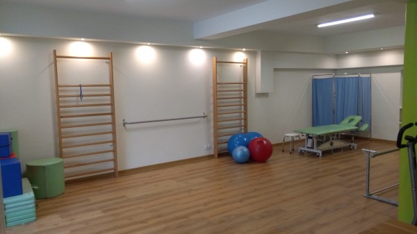 Sala do ćwiczeń z drabinkami gimnastycznymi, piłkami rehabilitacyjnymi, leżanką i parawanem.