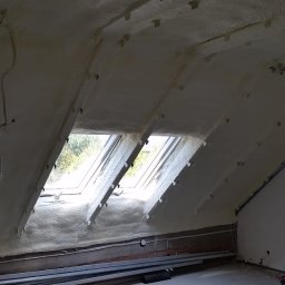 FIRMA HANDLOWO-USŁUGOWA Bartłomiej Biernat - Ocieplone pianką PUR poddasze z widocznymi oknami dachowymi, niezabezpieczonymi przewodami elektrycznymi i metalowymi profilami przy ścianie.