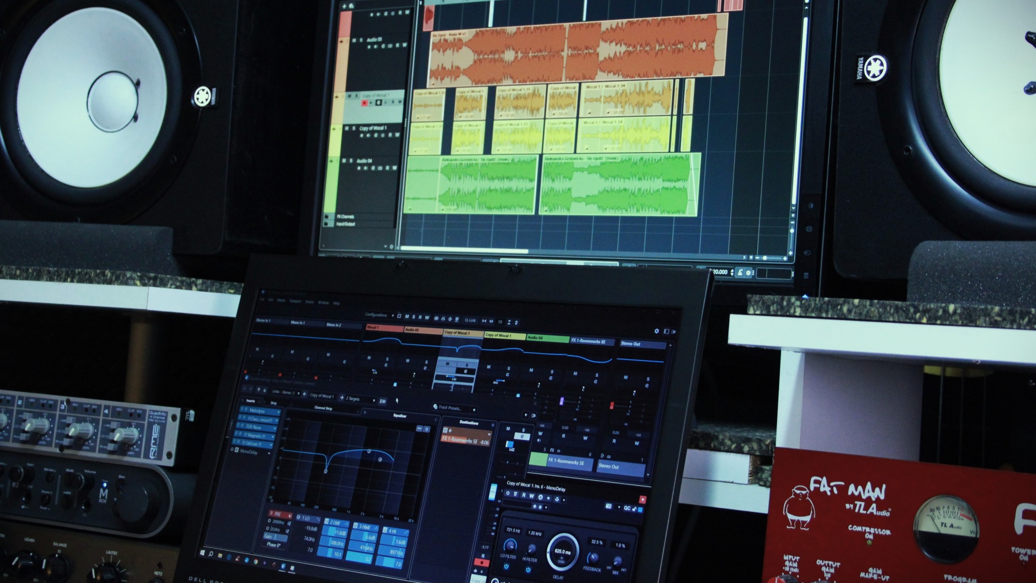 Ekran laptopa z oprogramowaniem DAW, monitory studyjne Yamaha, mikser audio i kompresor Fat Man w profesjonalnym studiu nagrań. Widok na interfejs edycji audio.