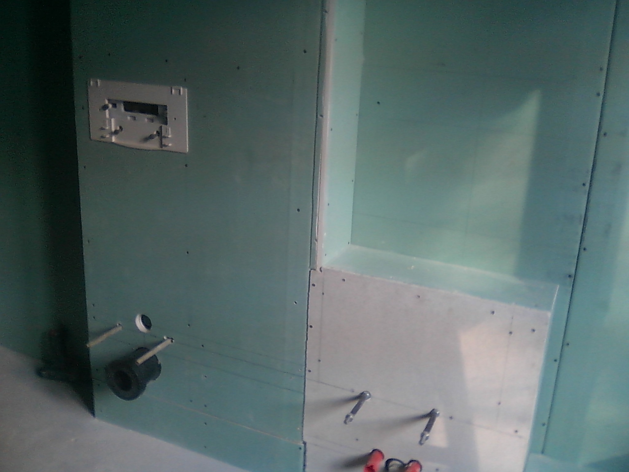 Konstrukcja z płyt gipsowo-kartonowych w łazience, widoczne elementy instalacji wodno-kanalizacyjnej i stelaż podtynkowy WC przed dalszym wykończeniem.