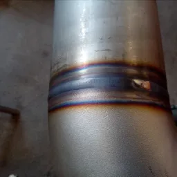 Spoina na rurociągu ze stali nierdzewnej, widoczne przebarwienia termiczne po procesie spawania.