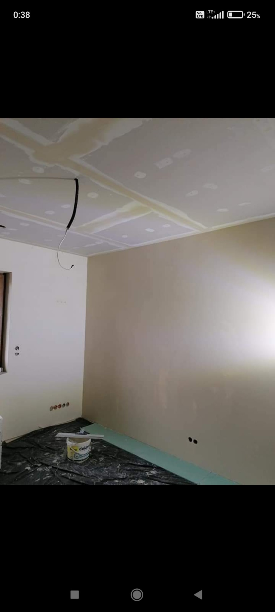 Pokój w trakcie prac wykończeniowych: ściany częściowo pokryte gładzią, sufit z płyt gipsowo-kartonowych ze szpachlowanymi łączeniami, podłoga zabezpieczona folią malarską, widoczne puszki...