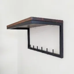 Półka ścienna z ciemnego drewna i metalu w stylu industrialnym, z haczykami na ubrania przymocowanymi do metalowej ramy, zamontowana na białej ścianie.