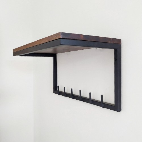 Półka ścienna z ciemnego drewna i metalu w stylu industrialnym, z haczykami na ubrania przymocowanymi do metalowej ramy, zamontowana na białej ścianie.