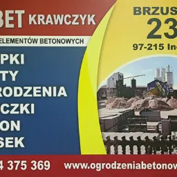 Baner reklamowy firmy Jarbet Krawczyk, producenta elementów betonowych: słupków, płyt, ogrodzeń, bloczków, betonu i piasku. W tle widok zakładu produkcyjnego z hałdami piasku i betonowymi elementami.