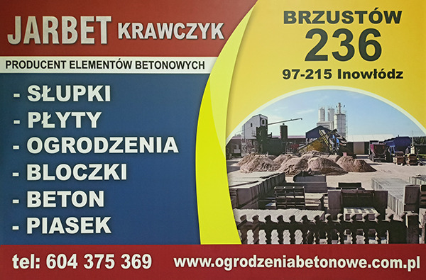 Baner reklamowy firmy Jarbet Krawczyk, producenta elementów betonowych: słupków, płyt, ogrodzeń, bloczków, betonu i piasku. W tle widok zakładu produkcyjnego z hałdami piasku i betonowymi elementami.