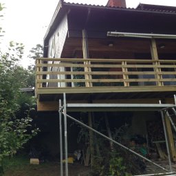 Kreative Home - Budowa drewnianego tarasu przy domu, widoczne rusztowanie i zgromadzone drewno.