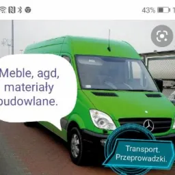 Zielony bus marki Mercedes z naklejkami informującymi o transporcie mebli, AGD i materiałów budowlanych, zaparkowany na chodniku.