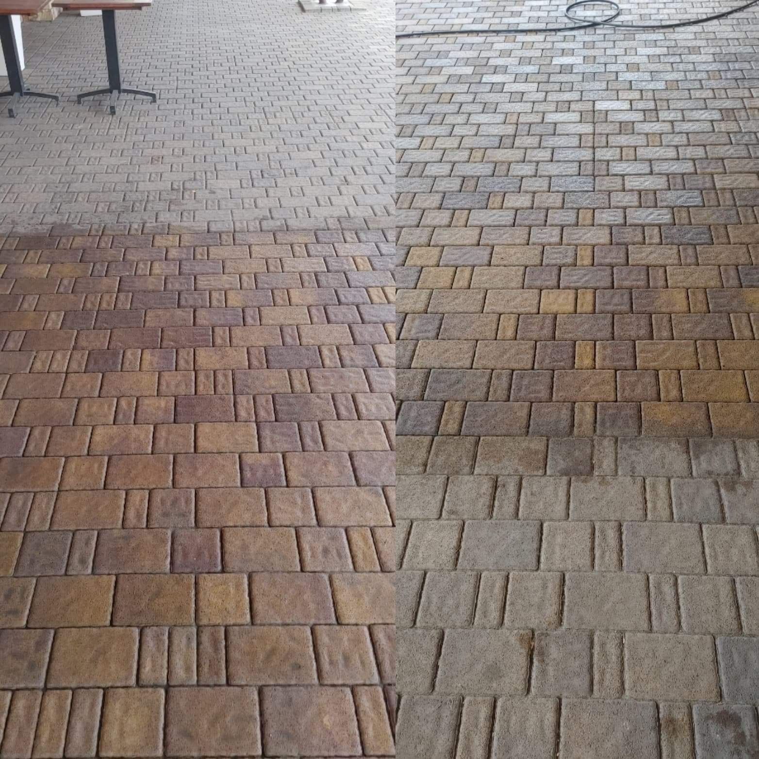 Częściowo wyczyszczona kostka brukowa na zewnątrz budynku, widoczna różnica w kolorze między wyczyszczoną a zabrudzoną powierzchnią, w tle stolik z dwoma nogami.