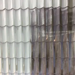 Częściowo umyty dach z szarej dachówki, ukazujący różnicę między czystą a brudną powierzchnią.