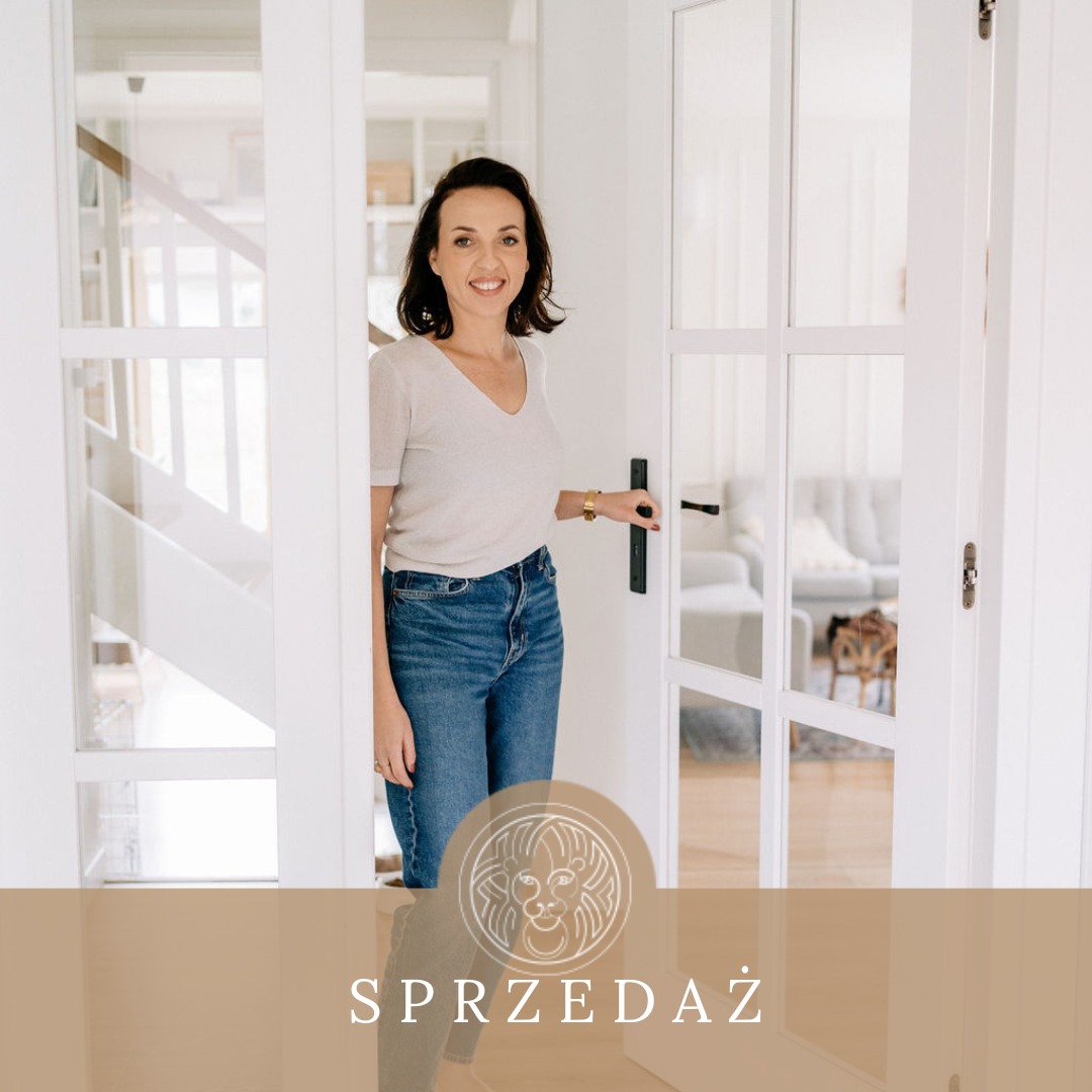 Uśmiechnięta kobieta otwiera przeszklone, białe drzwi do jasnego wnętrza z kanapą i schodami w tle.