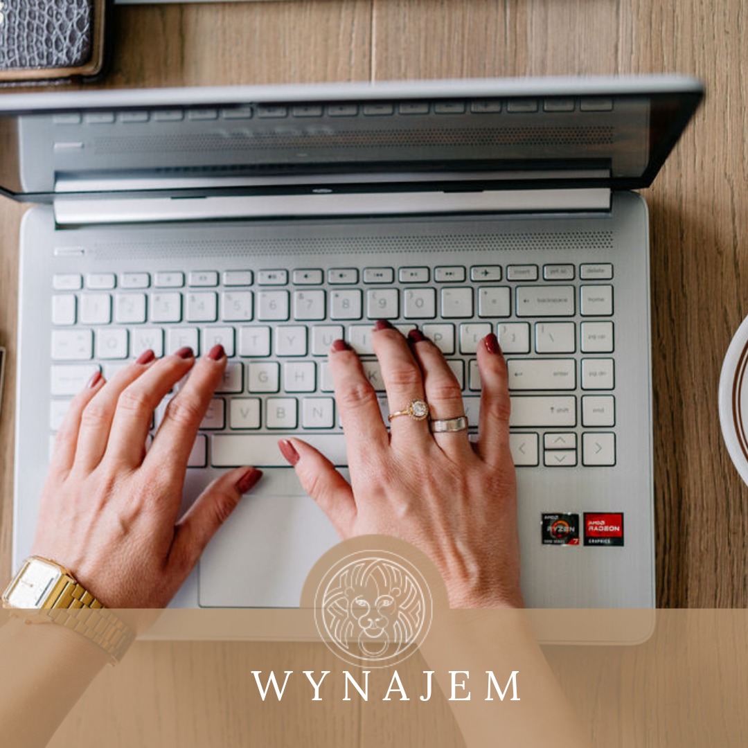 Kobieta z czerwonymi paznokciami i złotym zegarkiem pisze na laptopie z widocznym logo AMD Radeon Graphics na drewnianym biurku.