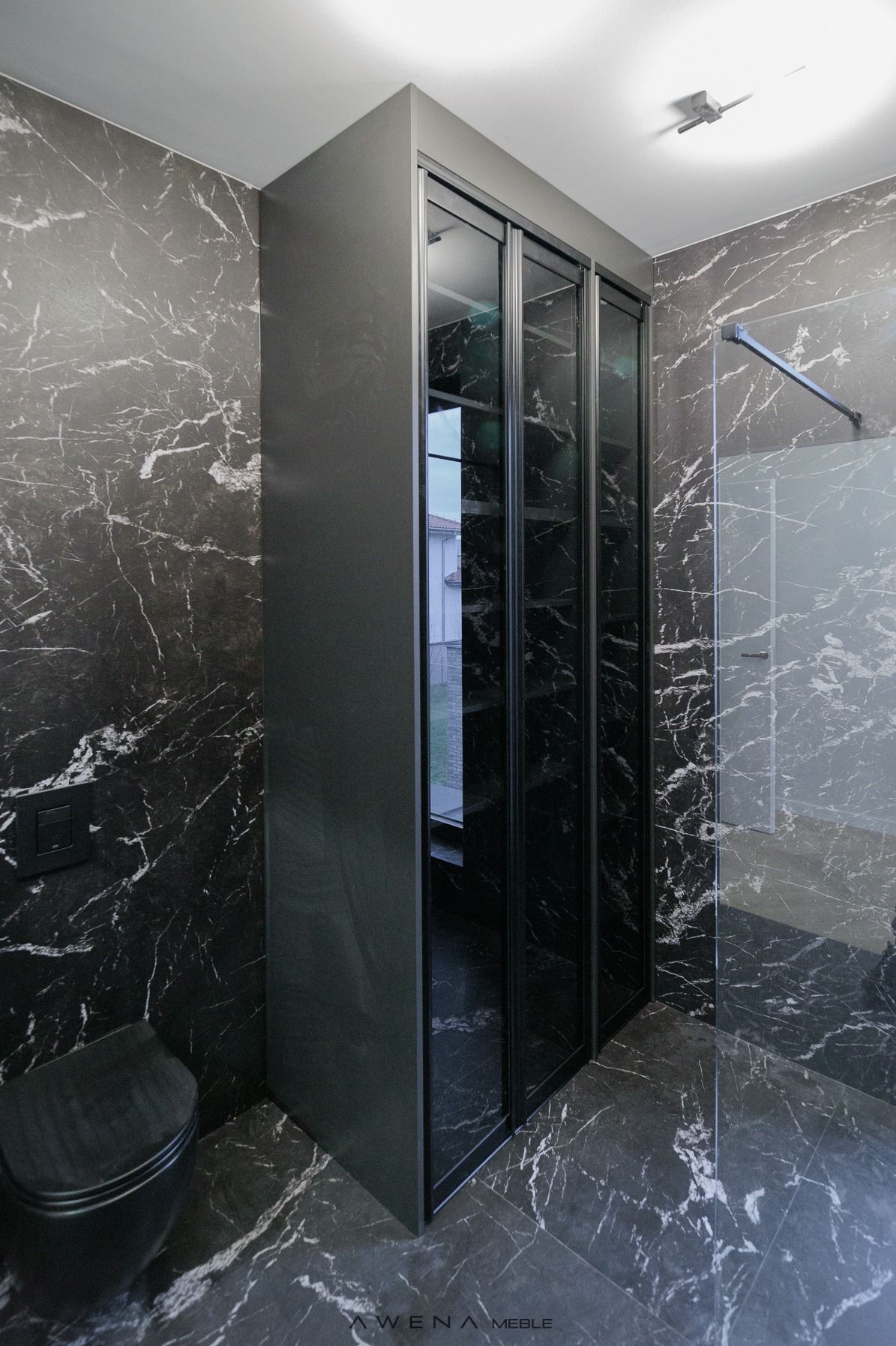 Nowoczesna łazienka z szafą wnękową z przesuwnymi, szklanymi drzwiami i marmurowym wykończeniem ścian oraz podłogi.