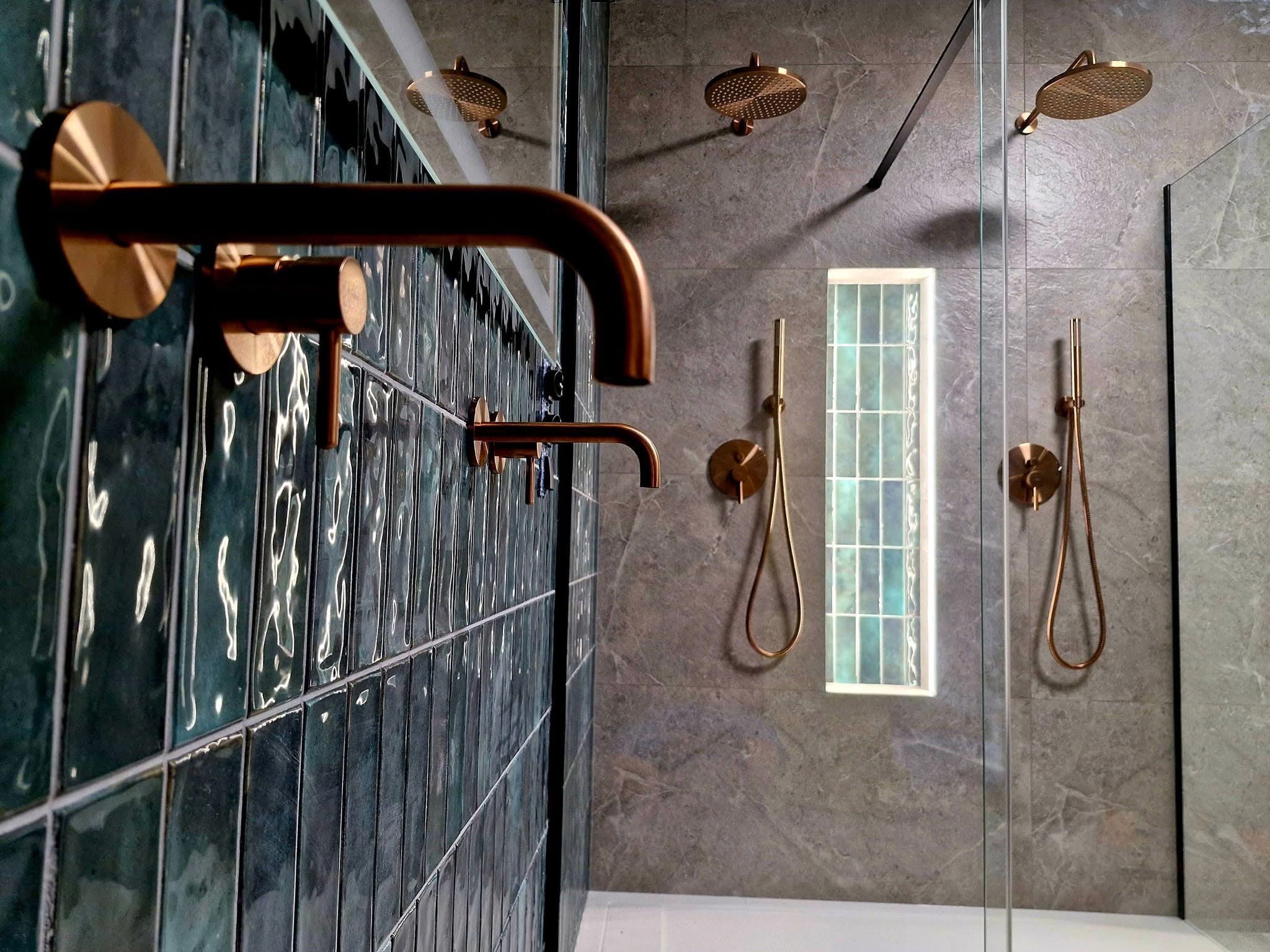 Nowoczesna łazienka: błyszczące, ciemnozielone płytki ścienne i miedziana armatura, szklana kabina prysznicowa, okno z luksferami.