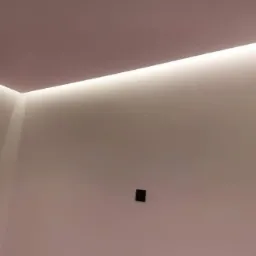 Ściana w odcieniach bieli z ukrytym oświetleniem LED pod sufitem w Wałczu, widoczny gładki tynk i czarny włącznik.