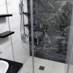 Nowoczesna łazienka z kabiną prysznicową typu walk-in, wykończona białymi i czarnymi płytkami imitującymi marmur, z czarnymi półkami i armaturą w kolorze chromu.