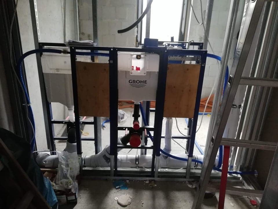 Stelaż podtynkowy Grohe zamontowany w konstrukcji z profili stalowych, widoczne rury i elementy instalacji hydraulicznej w trakcie montażu.