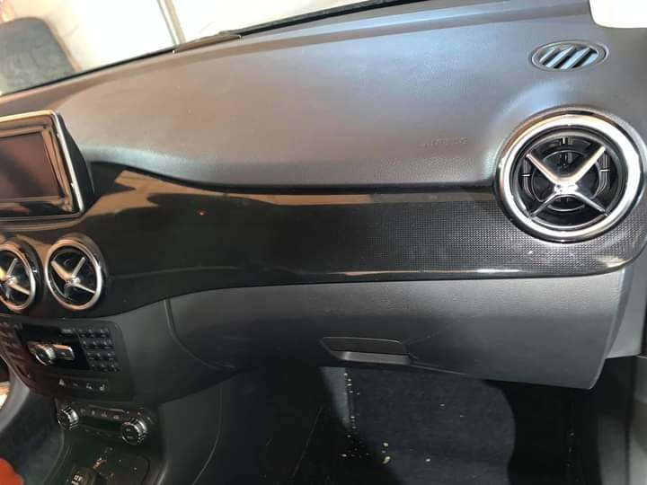 Wnętrze samochodu z widoczną deską rozdzielczą, nawiewami z chromowanymi obwódkami i elementami sterowania, po czyszczeniu.