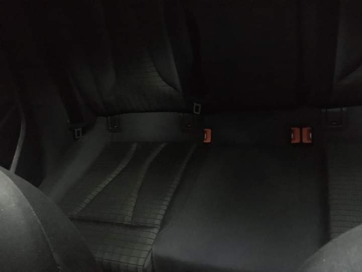 Ciemne, niemal czarne wnętrze samochodu, widok na tylną kanapę z widocznymi mocowaniami ISOFIX.