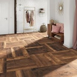 Kalmat - Wzorzysta podłoga z płytek imitujących drewno ułożonych w jodełkę na jasnym tle z dekoracyjnymi elementami wnętrza, takimi jak wieszak na ubrania, poduszki i zasłona.