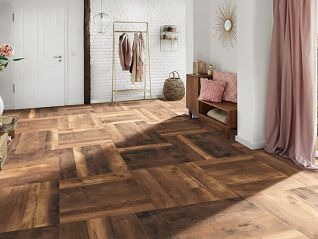 Wzorzysta podłoga z płytek imitujących drewno ułożonych w jodełkę na jasnym tle z dekoracyjnymi elementami wnętrza, takimi jak wieszak na ubrania, poduszki i zasłona.