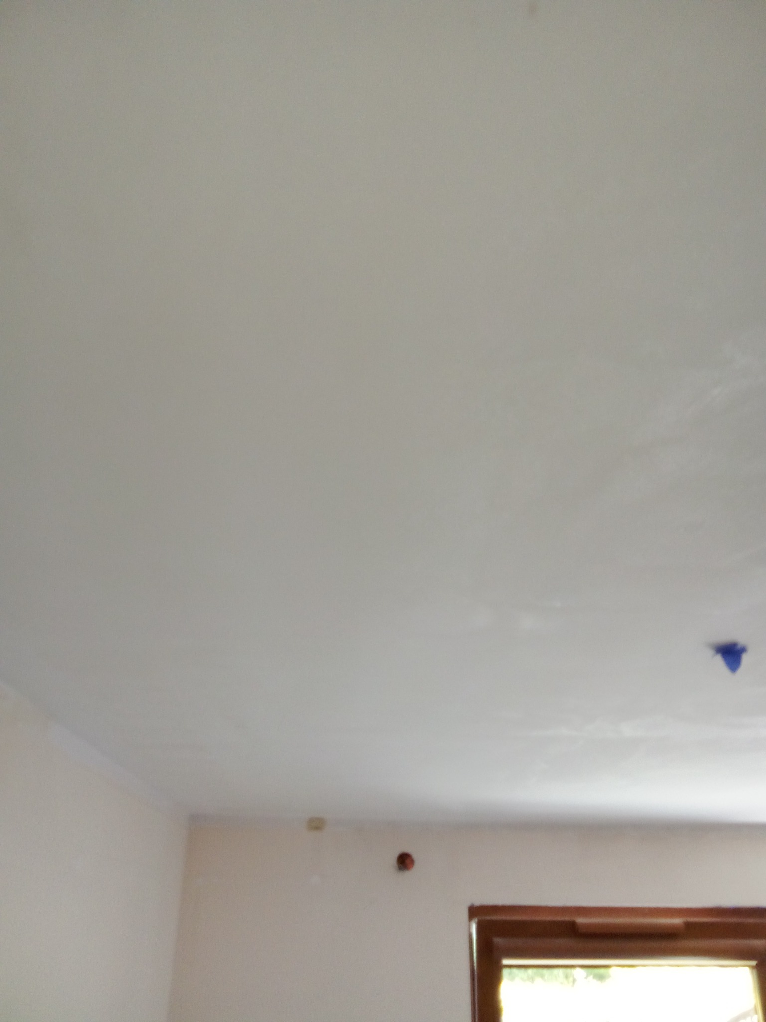 Biały sufit po szpachlowaniu, widoczny fragment okna i ściany z zaznaczonym otworem, gotowy do malowania.