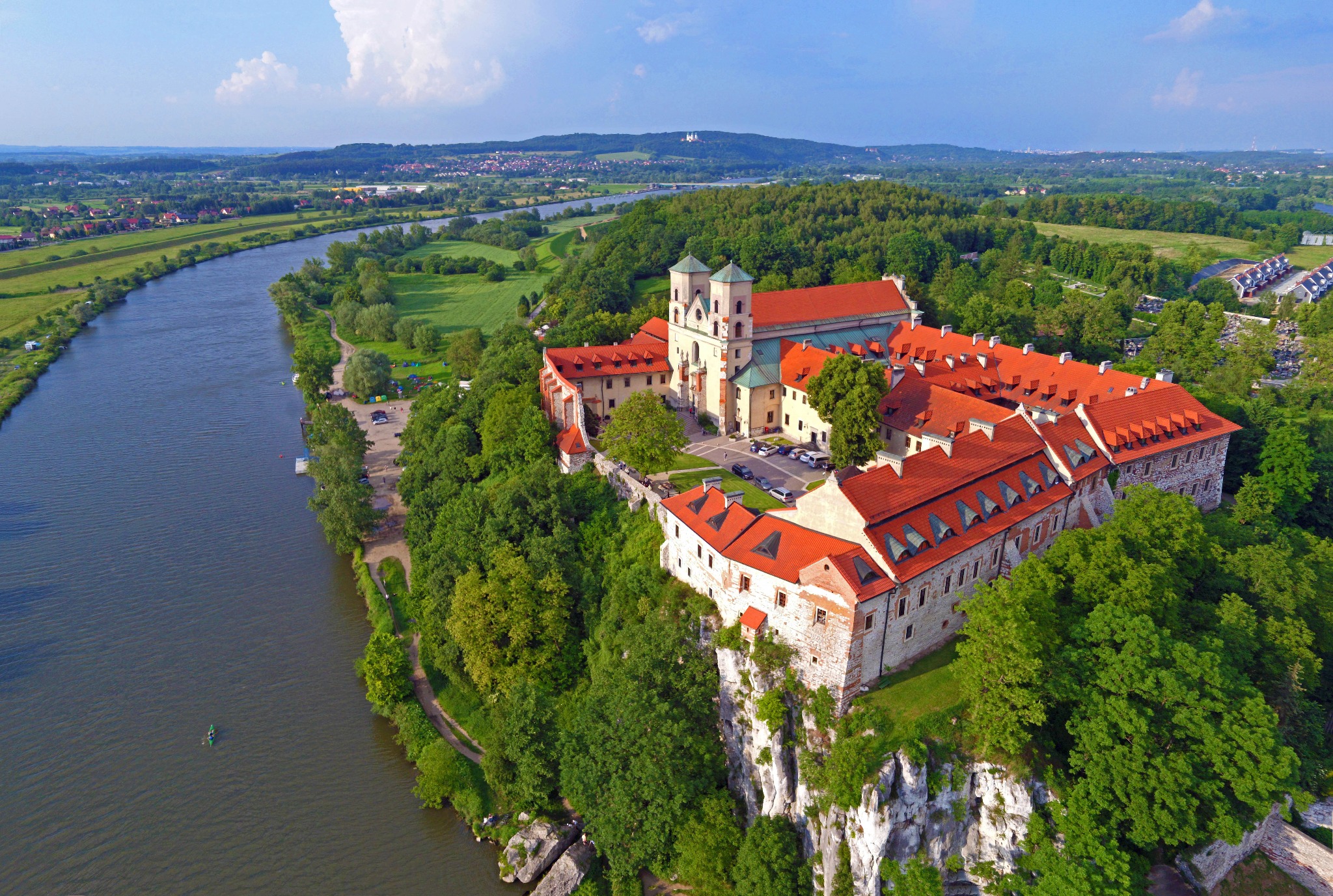 Klasztor w Tyńcu, widok z lotu ptaka na budynek z czerwonym dachem, położony na skale nad Wisłą, z widoczną panoramą okolicy.