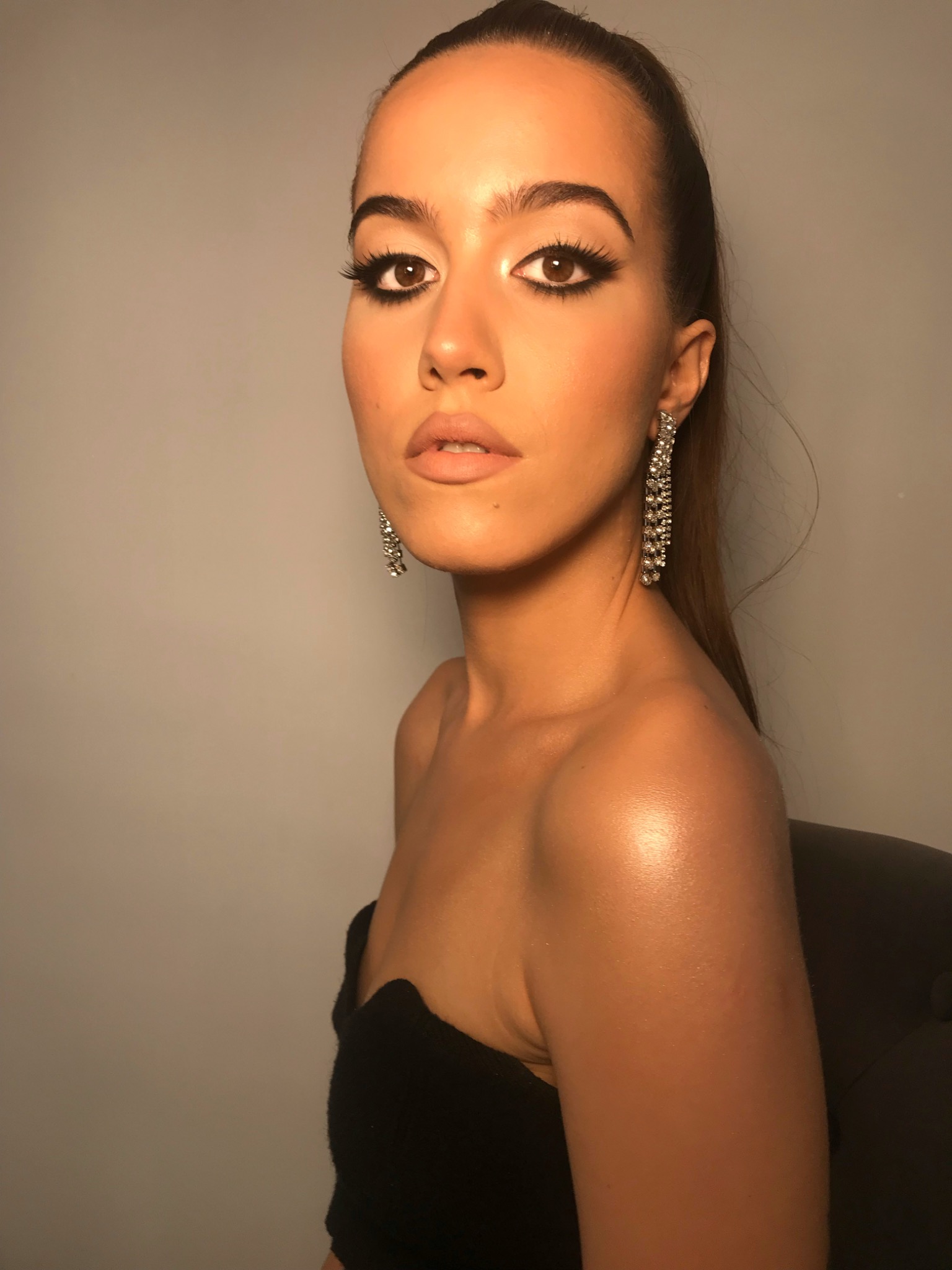 Portret kobiety w Stargardzie z wieczorowym makijażem oczu, podkreślonym eyelinerem i sztucznymi rzęsami, oraz długimi, błyszczącymi kolczykami.