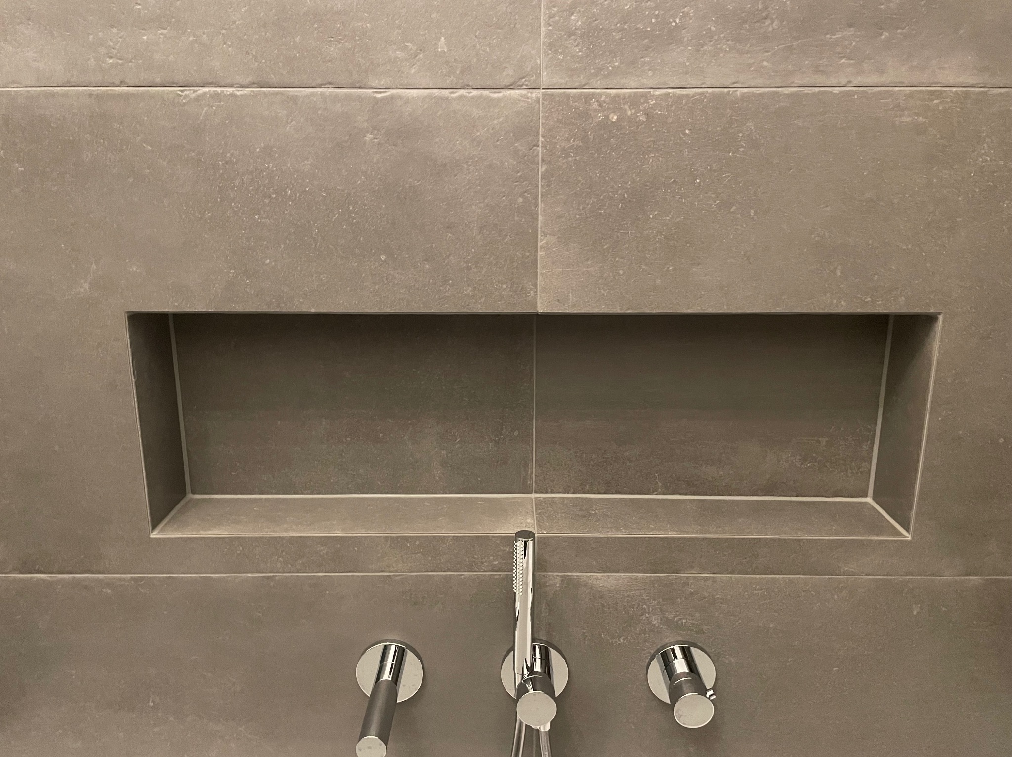 Szare płytki w łazience w Jeleniej Górze z wnęką i chromowaną armaturą.