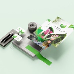 Wojoweb- Nowoczesne strony internetowe - Mockup materiałów reklamowych dla firmy ogrodniczej: ulotka, wizytówki, ołówki i spinacze biurowe na geometrycznych blokach w pastelowej tonacji.
