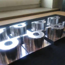 Rząd precyzyjnie wykonanych, błyszczących, metalowych elementów z otworem, ustawionych na czarnej macie, oświetlonych jasnym światłem.